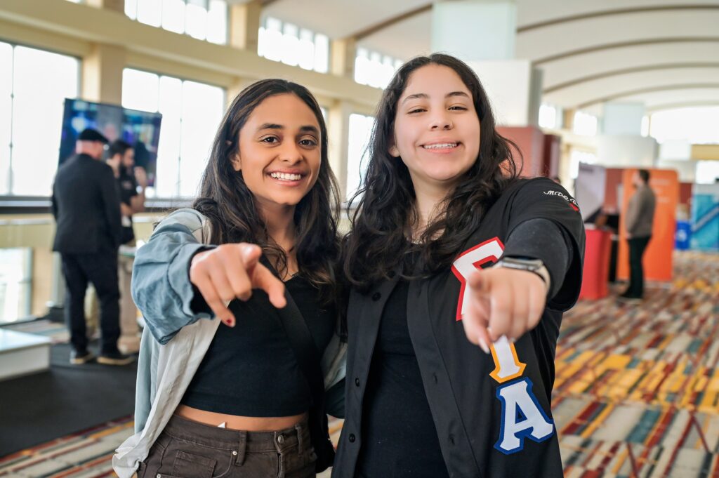 two college students smiling pointing at camera