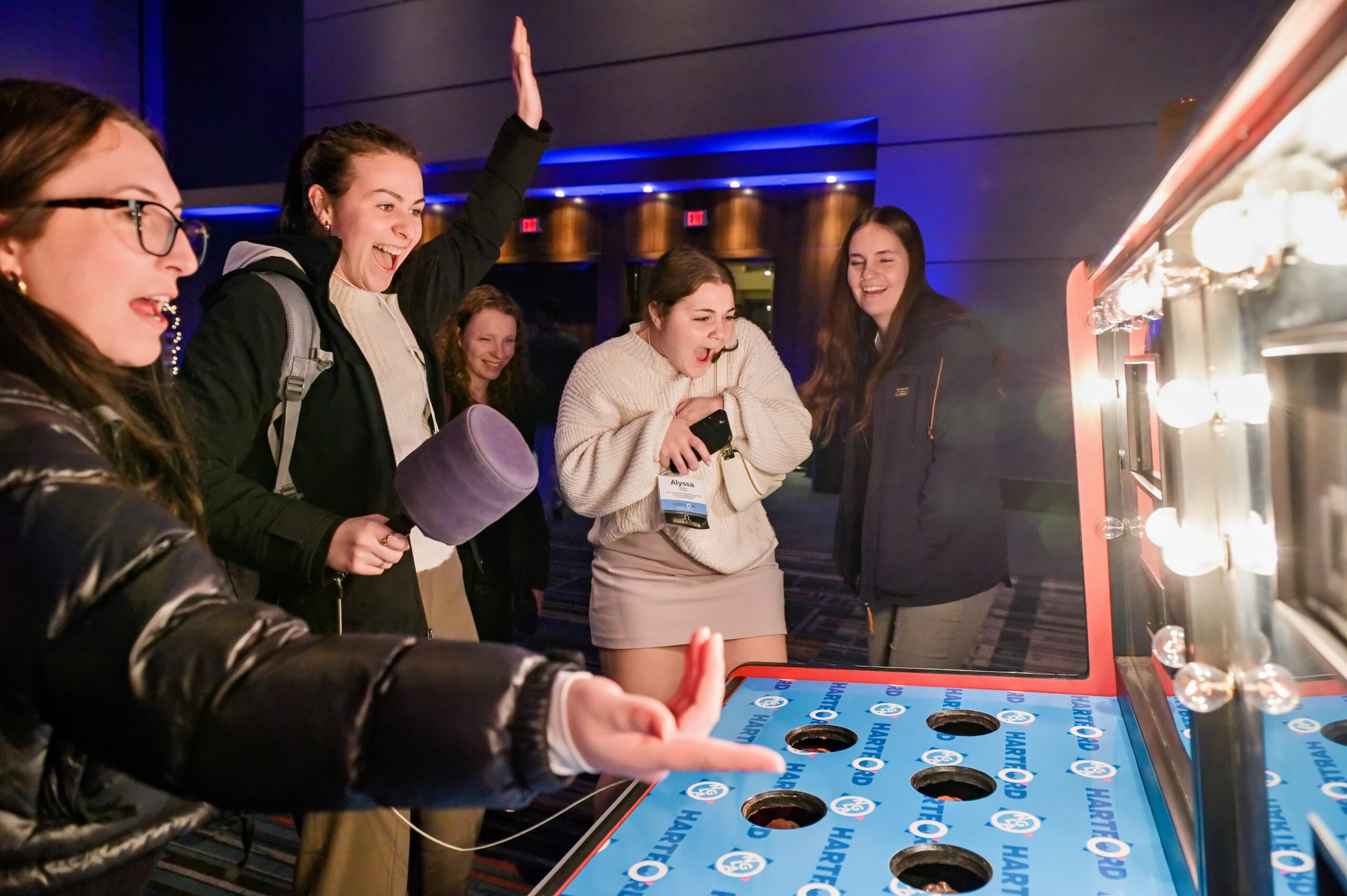 group of college students playing arcade whac-a-mole game